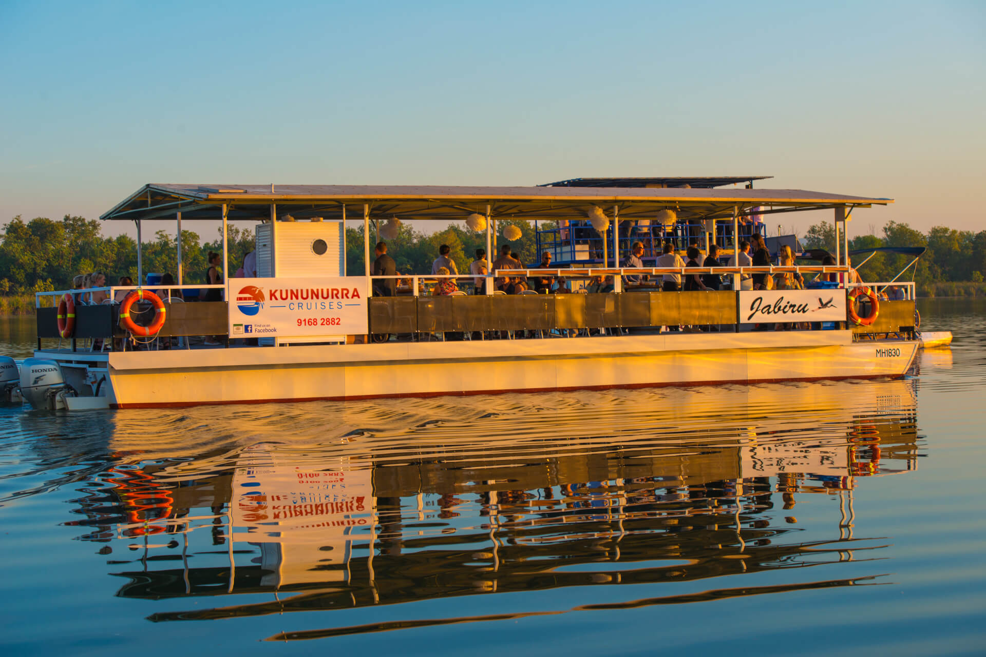 People onboard a boat on the water at sunset.