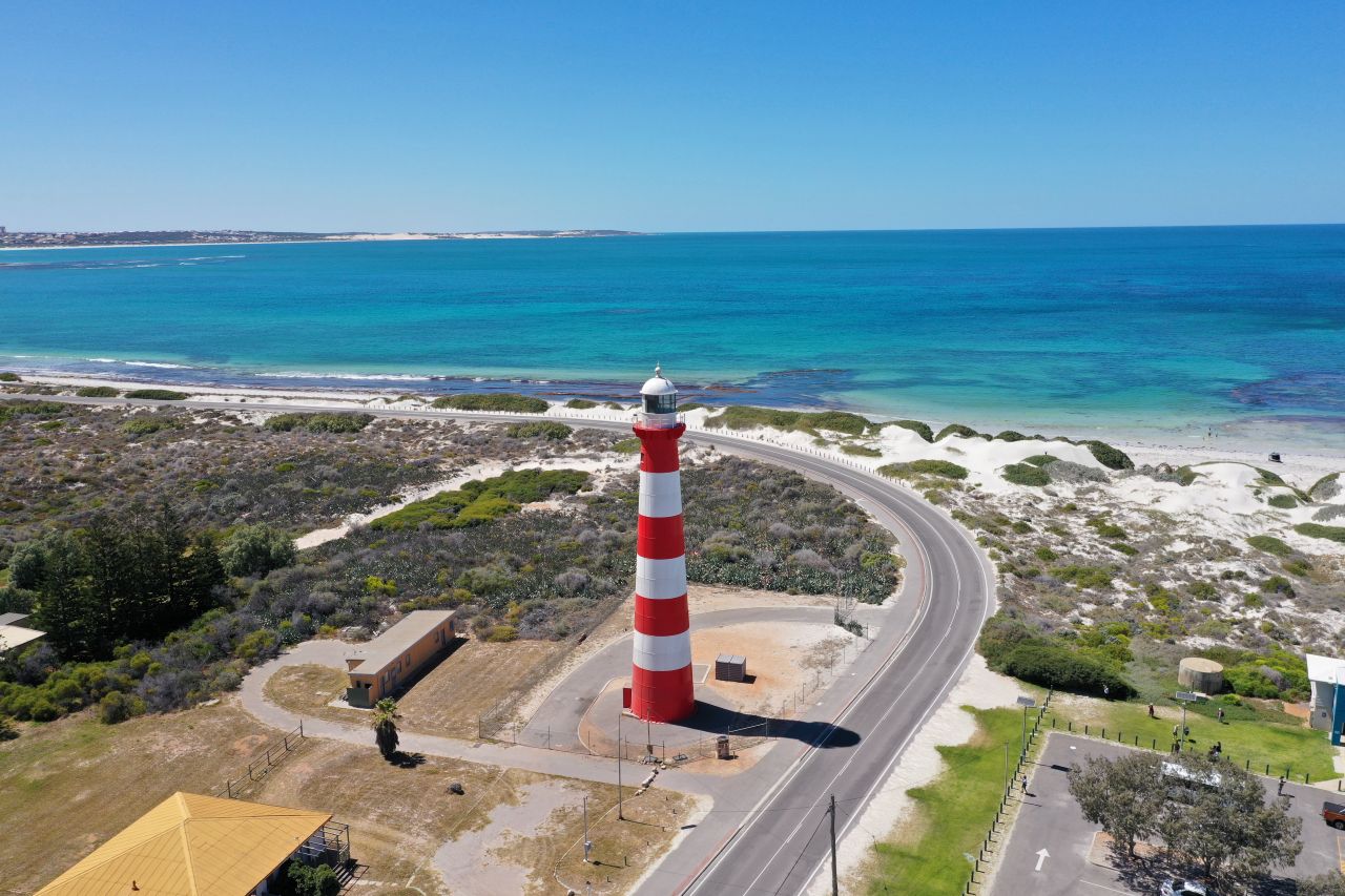A red and white striped lighthouse in front of the ocean in Geraldton. 