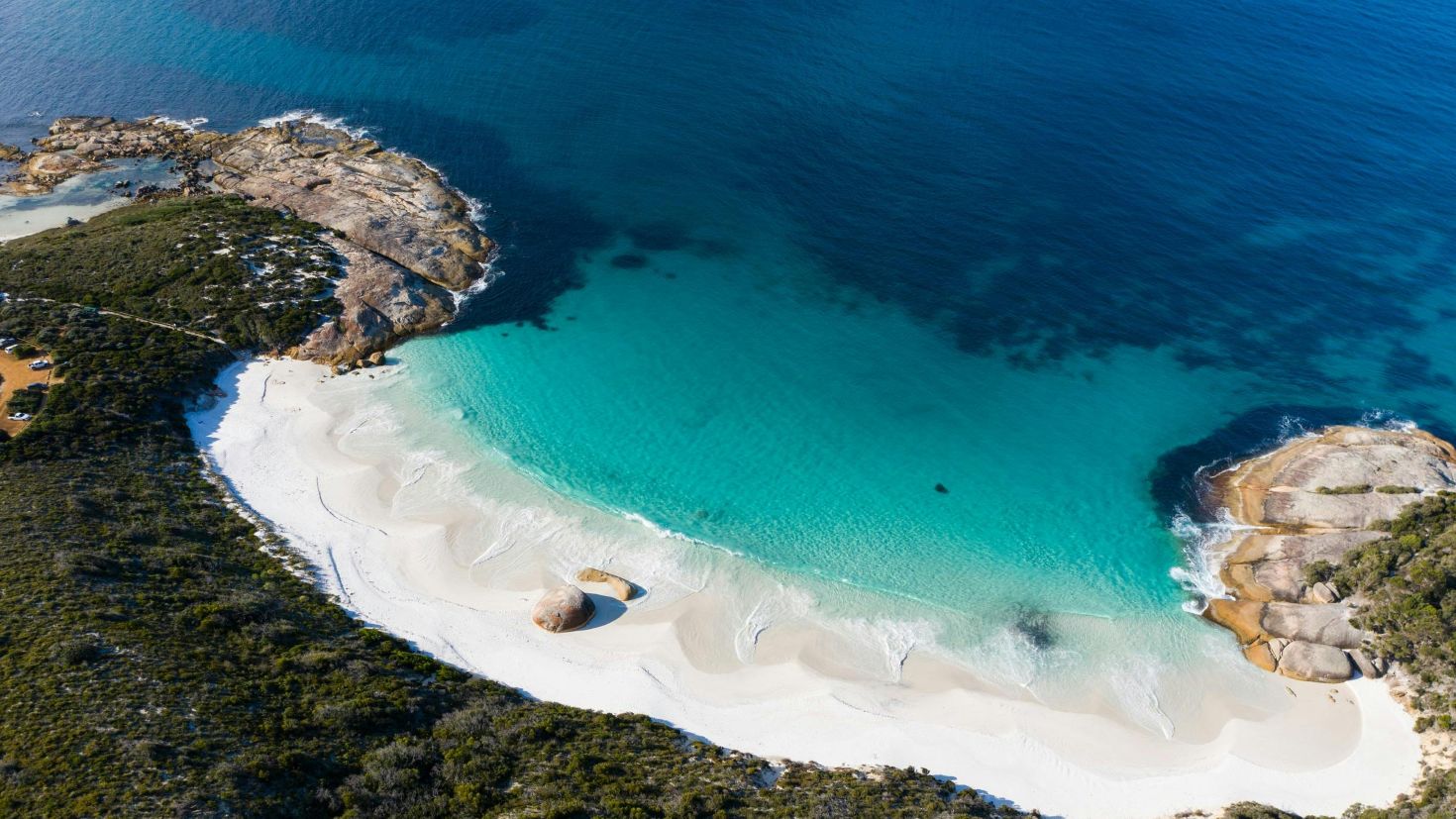 A picture of a bay with 2 rocks in the middle of the beach.