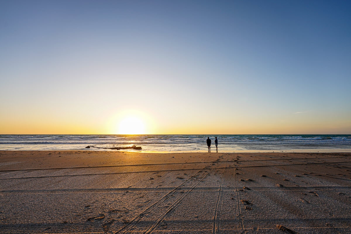 Broome sunset views at Cable Beach, two travellers standing in the distance.