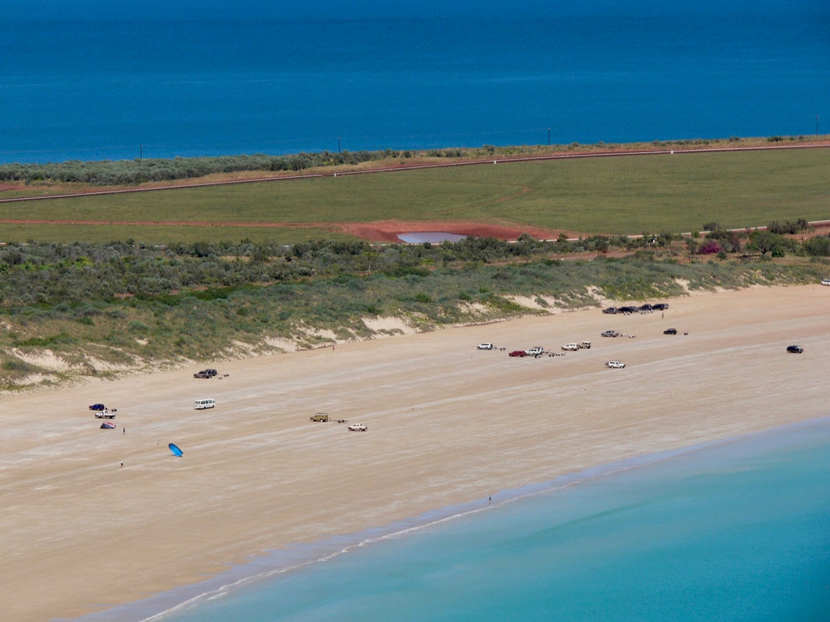Aerial view over the beach in Broome with many 4WDs heading off road.
