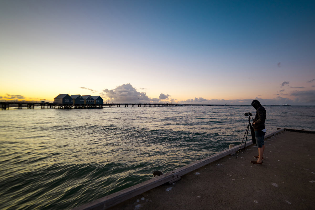 Photographers taking pictures of Busselton Jetty as the sun sets in Western Australia.