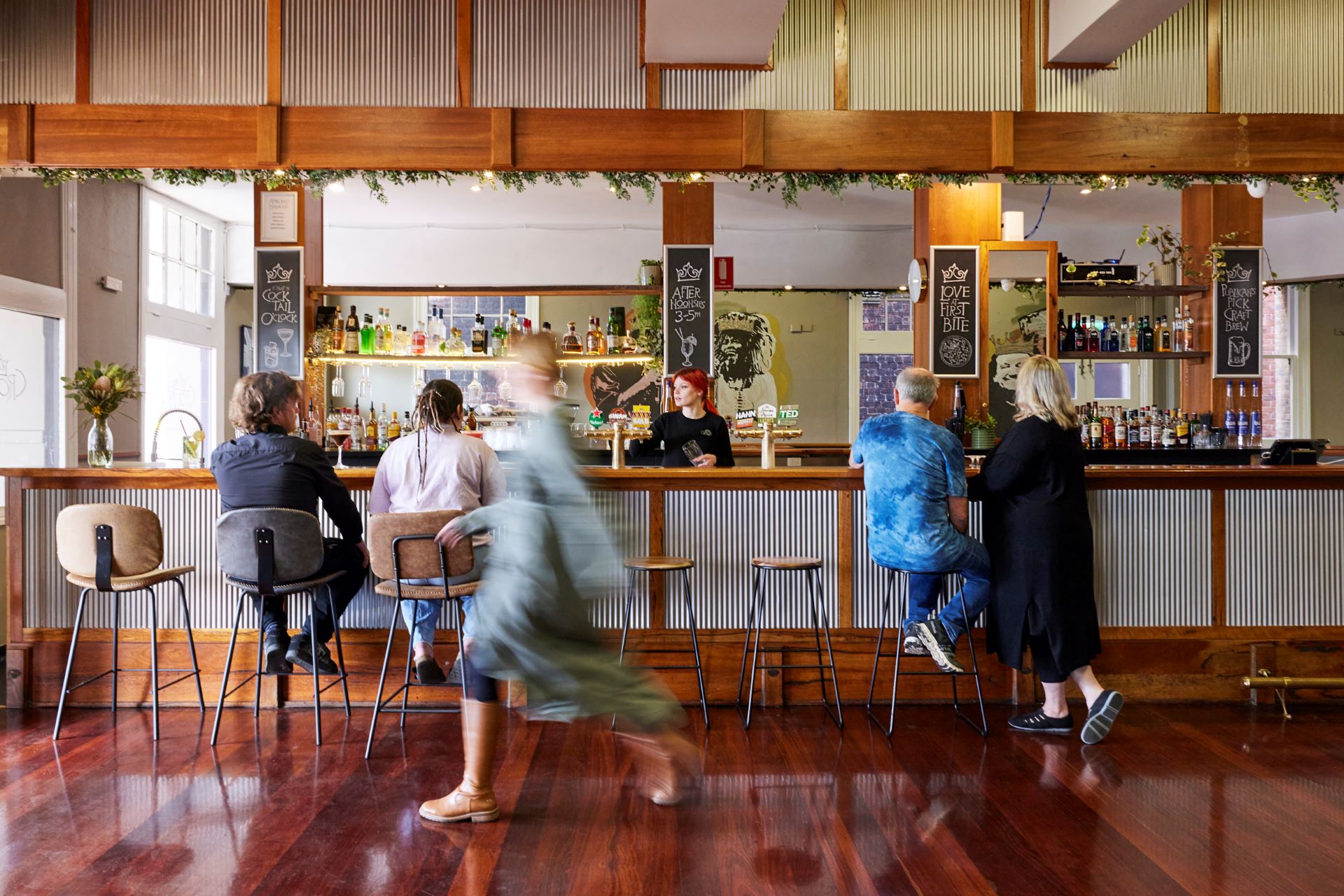 Patrons sit on barstools in front of a bar.