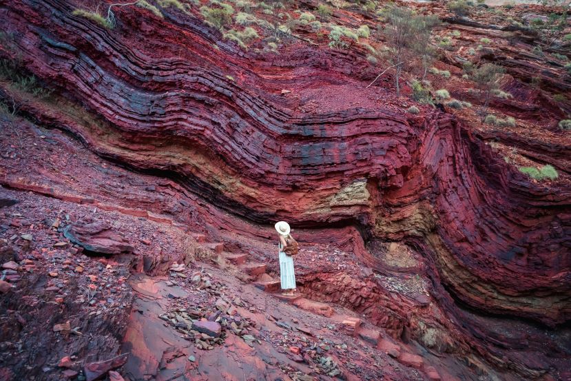 A woman stands in front of a rock wall