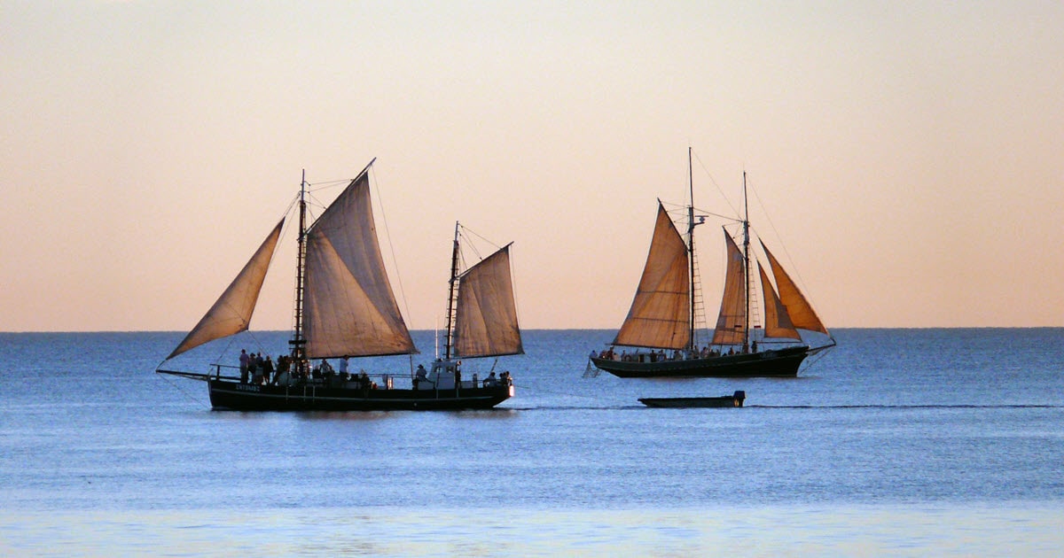 Pearl luggers off Cable Beach in Broome as the sun sets over the water.