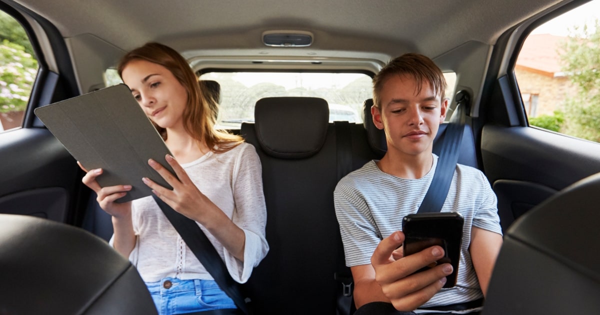 Kids using phones and tablets in back seat on WA road trip.