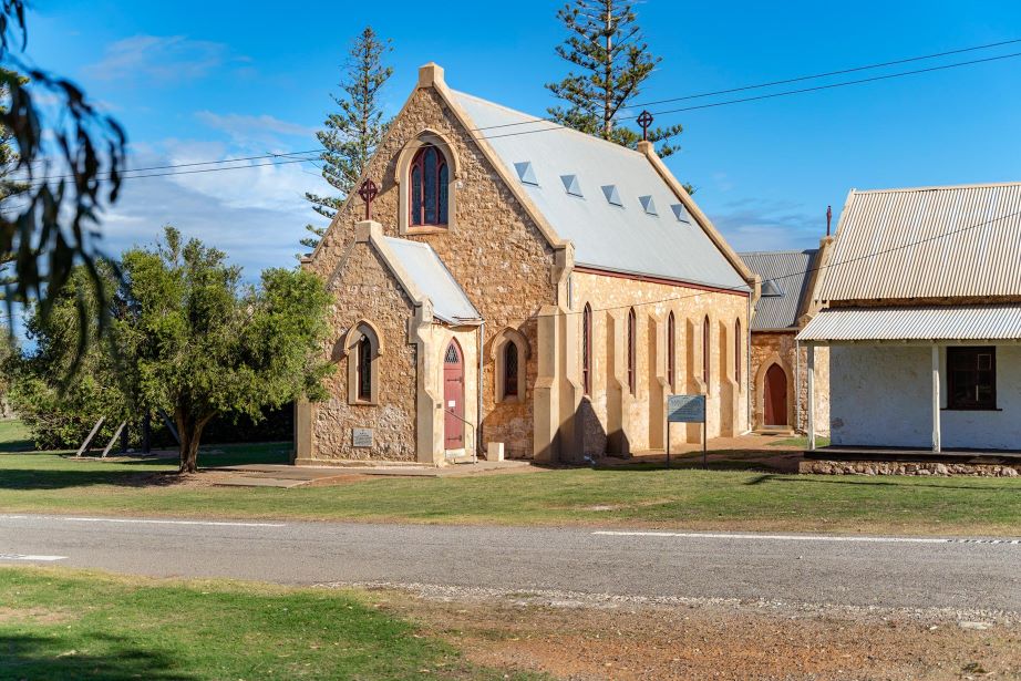 A limestone church in front of a road