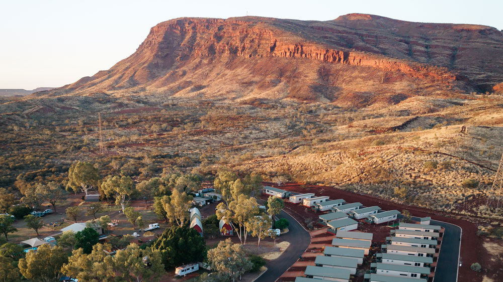 A caravan park sits at the base of a mountain