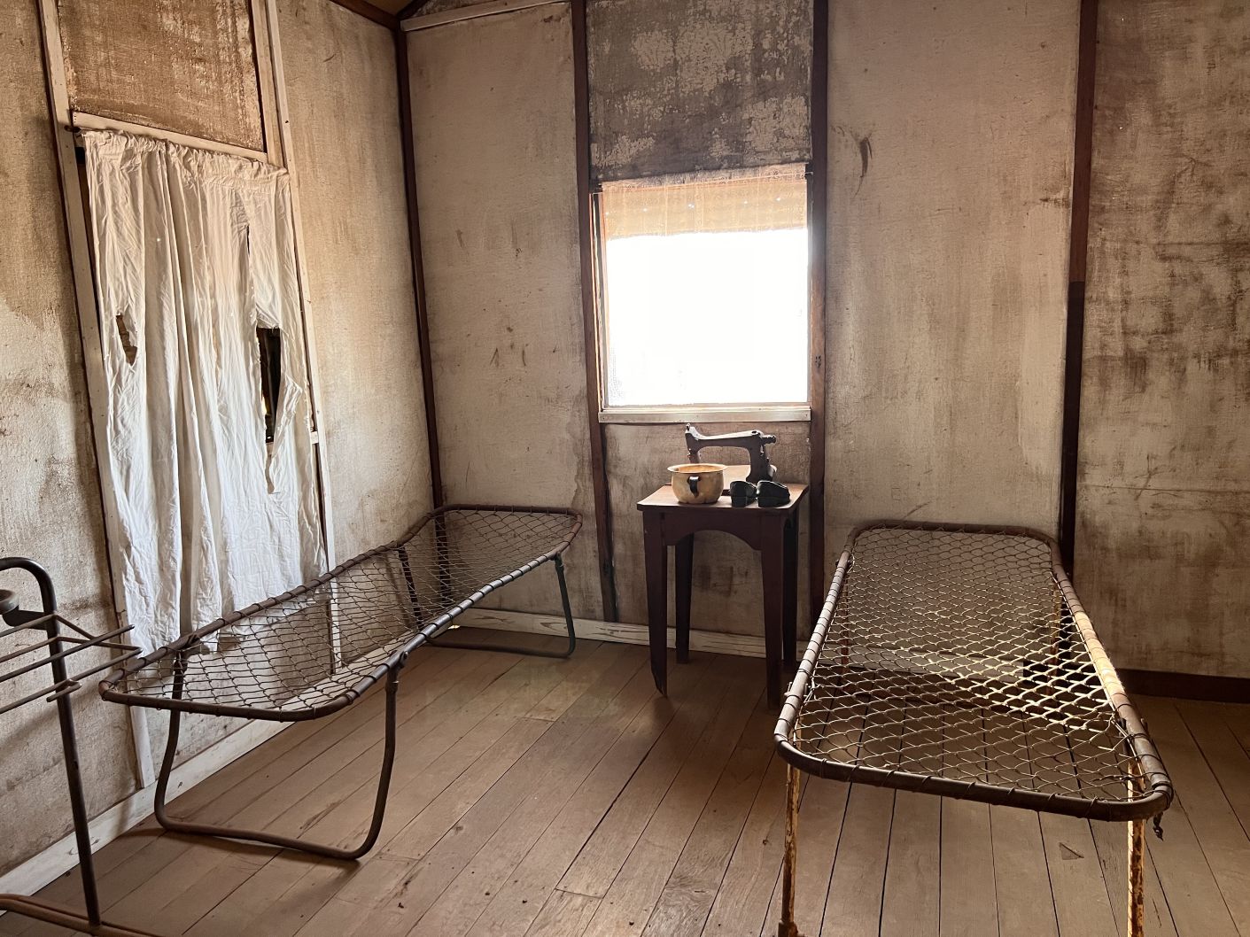2 metal bed frames on floorboards in an abandoned house.