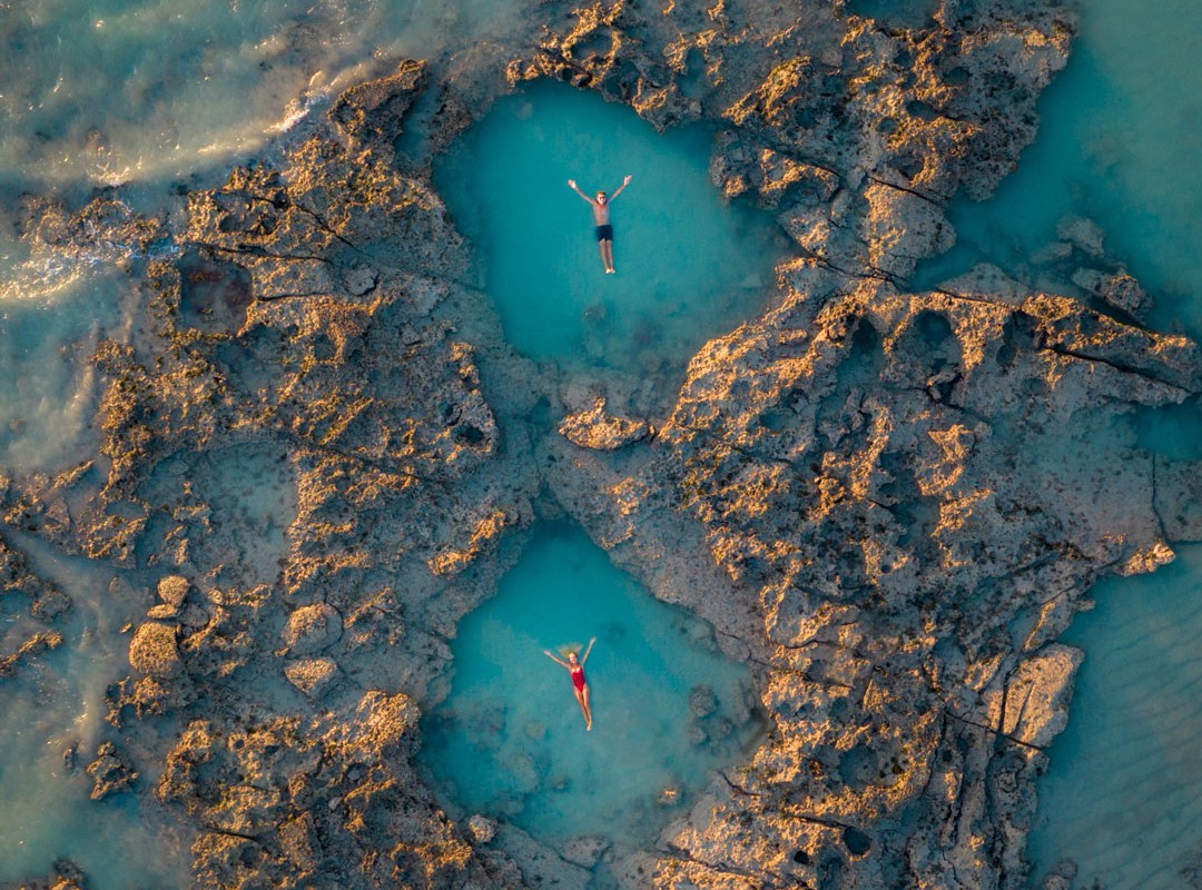 2 people sloating in seperate rock pools