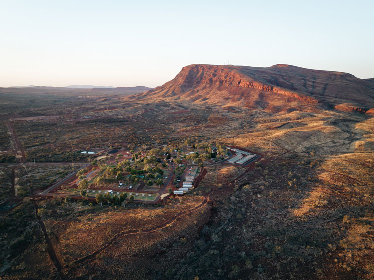 a drone shot of a caravan park at the foot of a mountain.