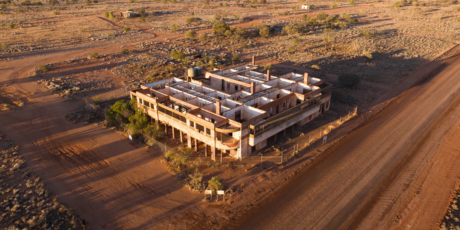 An aerial image of an abandoned building in the middle of the desert.