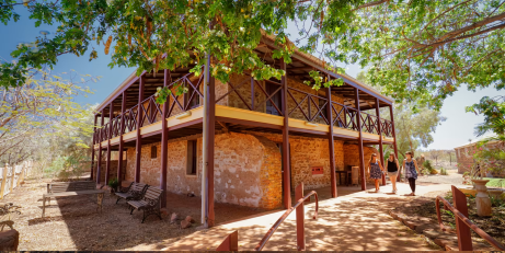 3 women walk by a 2 storey stone building.