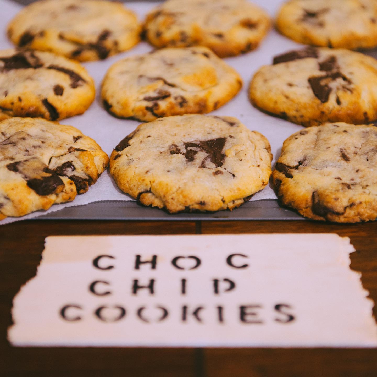 chocolate chip cookies on the table behind a sign that says choc chip cookies